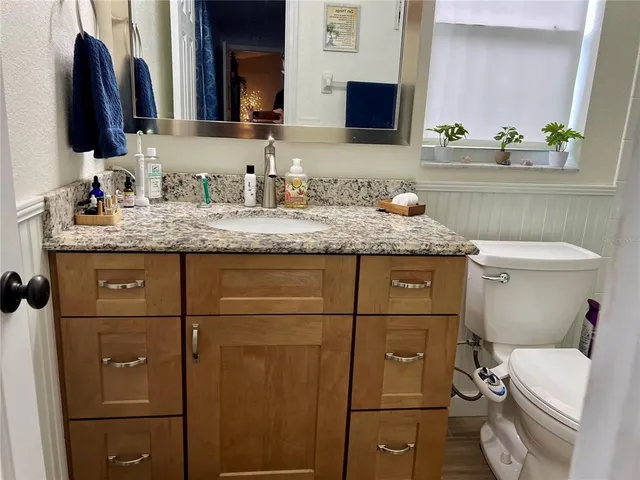 a bathroom with a granite countertop toilet sink and mirror