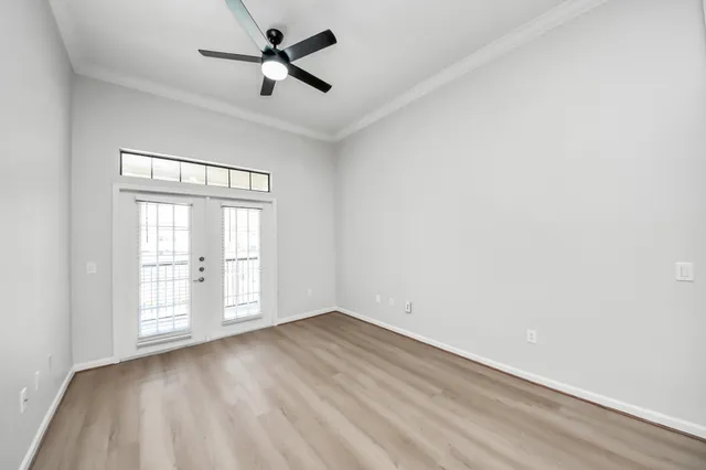 an empty room with wooden floor fan and windows