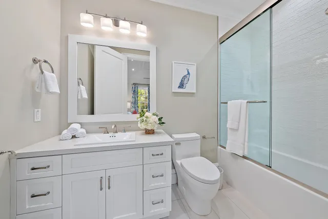 a bathroom with a toilet a sink a mirror a vanity and window