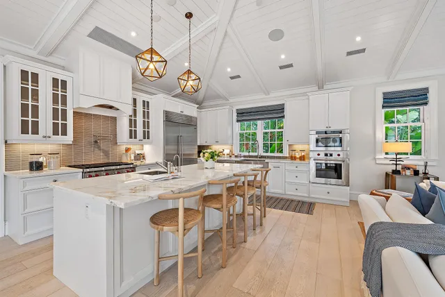 a kitchen with stainless steel appliances granite countertop a stove a sink a oven a dining table and chairs with wooden floor