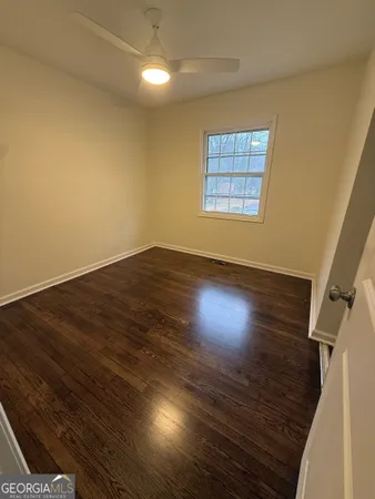 an empty room with wooden floor windows and closet