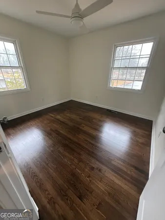 an empty room with wooden floor and windows