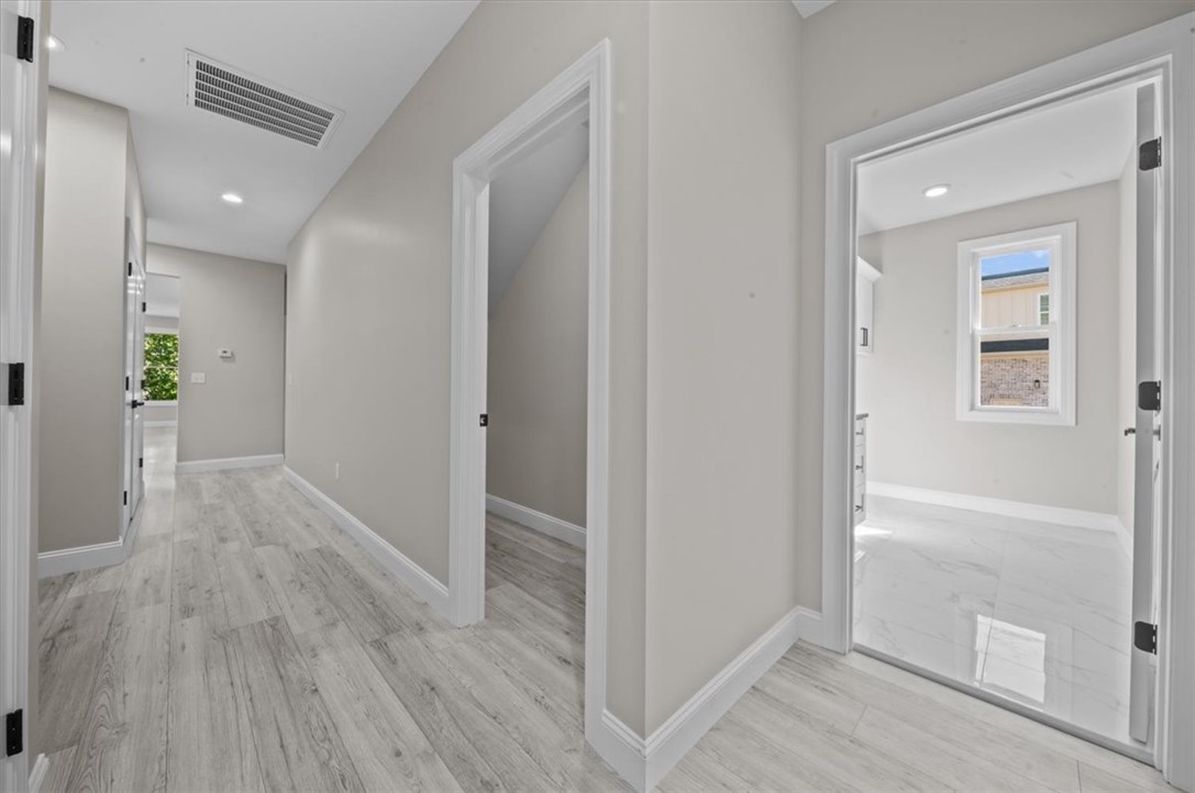 105 Bree Drive Anderson, SC 29621 - Photo 16 of 48 A well-lit corridor with sleek, light wood-style flooring extends toward inviting rooms.