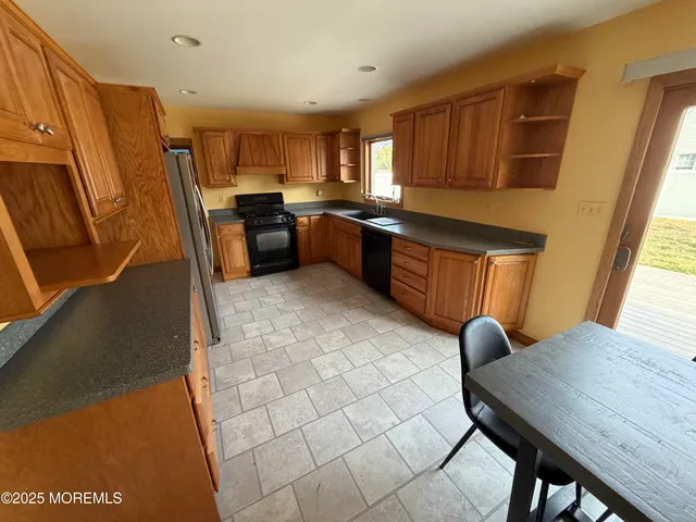 a kitchen with stainless steel appliances wooden cabinets a stove a sink a dining table and chairs