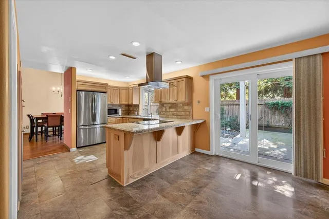 a kitchen with stainless steel appliances granite countertop a stove top oven a sink and a refrigerator