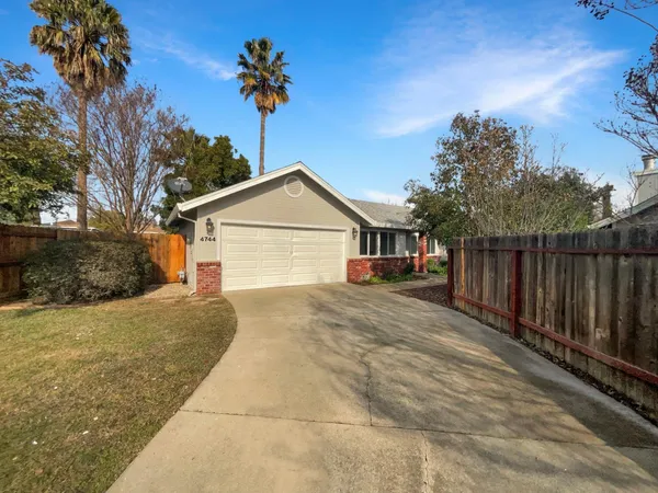 a view of house with wooden fence and trees in the background