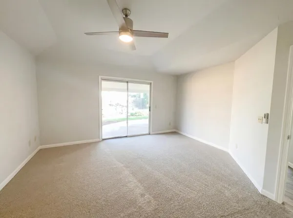 an empty room with a chandelier fan and windows