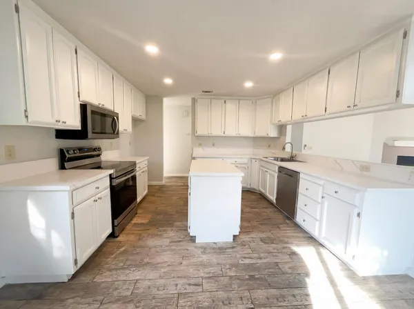 a large kitchen with stainless steel appliances granite countertop a stove top oven a sink dishwasher and a refrigerator