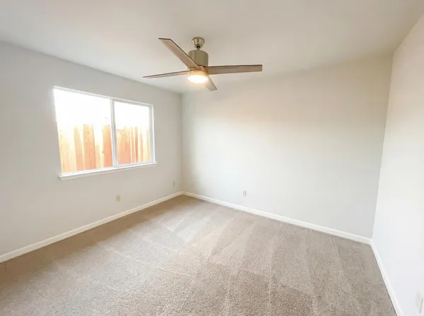 an empty room with a window and a fan