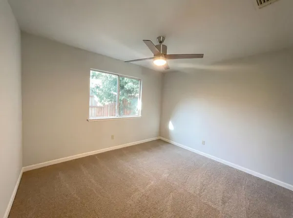 an empty room with a window and ceiling fan