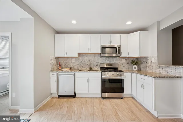 a kitchen with granite countertop white cabinets stainless steel appliances and a sink