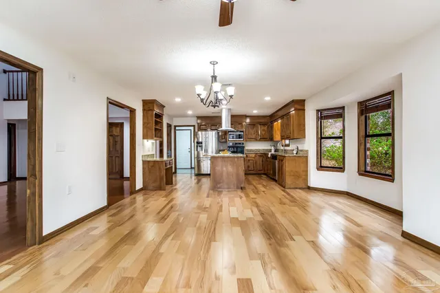 a view of empty room with wooden floor and ceiling fan