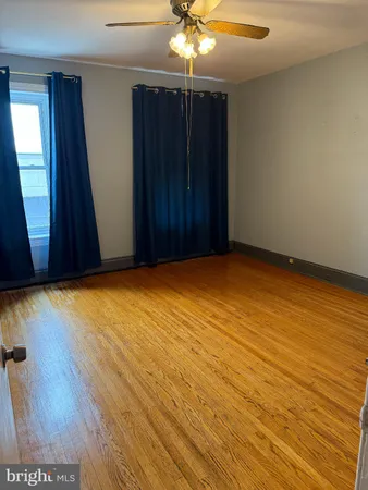 an empty room with wooden floor and chandelier fan