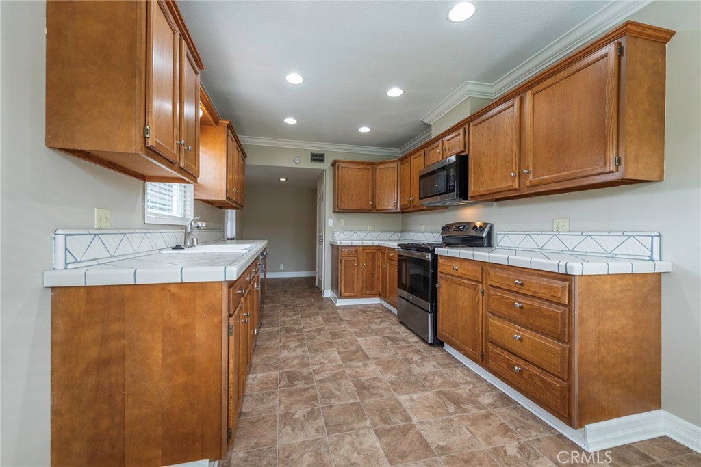 4697 Sierra Street Riverside, CA 92504 - Photo 18 of 51 a kitchen with stainless steel appliances granite countertop wooden cabinets a stove a sink and a microwave