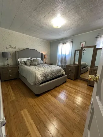 a spacious bedroom with a bed and wooden floor