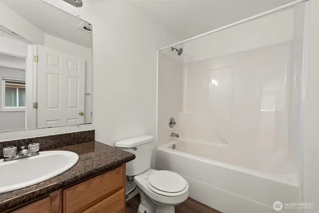 a bathroom with a granite countertop sink toilet mirror and shower