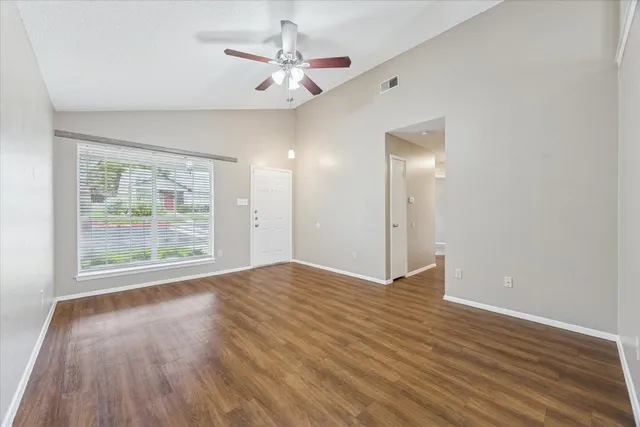 an empty room with wooden floor and windows