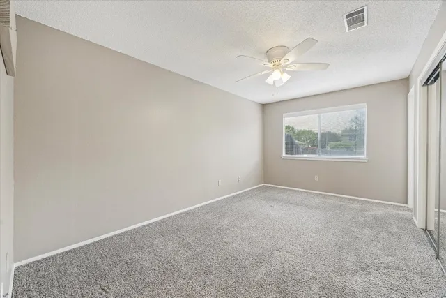 an empty room with a window and a ceiling fan