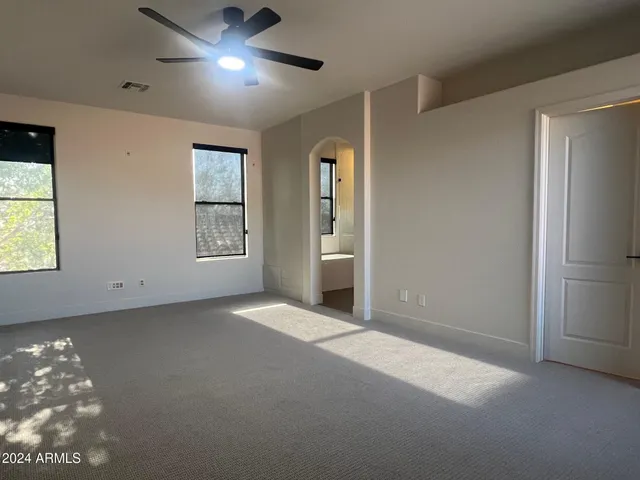 a view of an empty room with window and chandelier fan