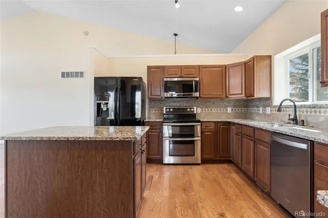 a kitchen with stainless steel appliances granite countertop a refrigerator a stove a sink and a microwave