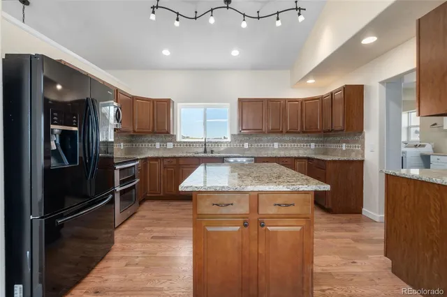 a kitchen with kitchen island granite countertop wooden cabinets and a stainless steel appliances
