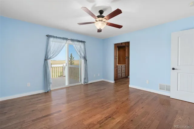 an empty room with wooden floor chandelier and windows