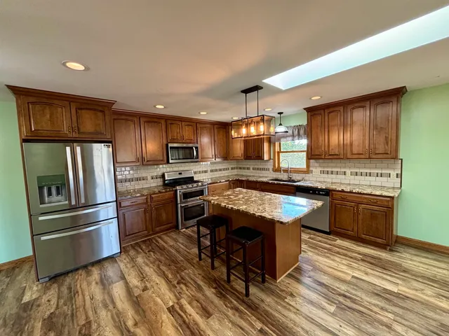 a kitchen with stainless steel appliances granite countertop a stove refrigerator and a microwave oven