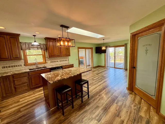 a kitchen with kitchen island granite countertop wooden floors and a sink