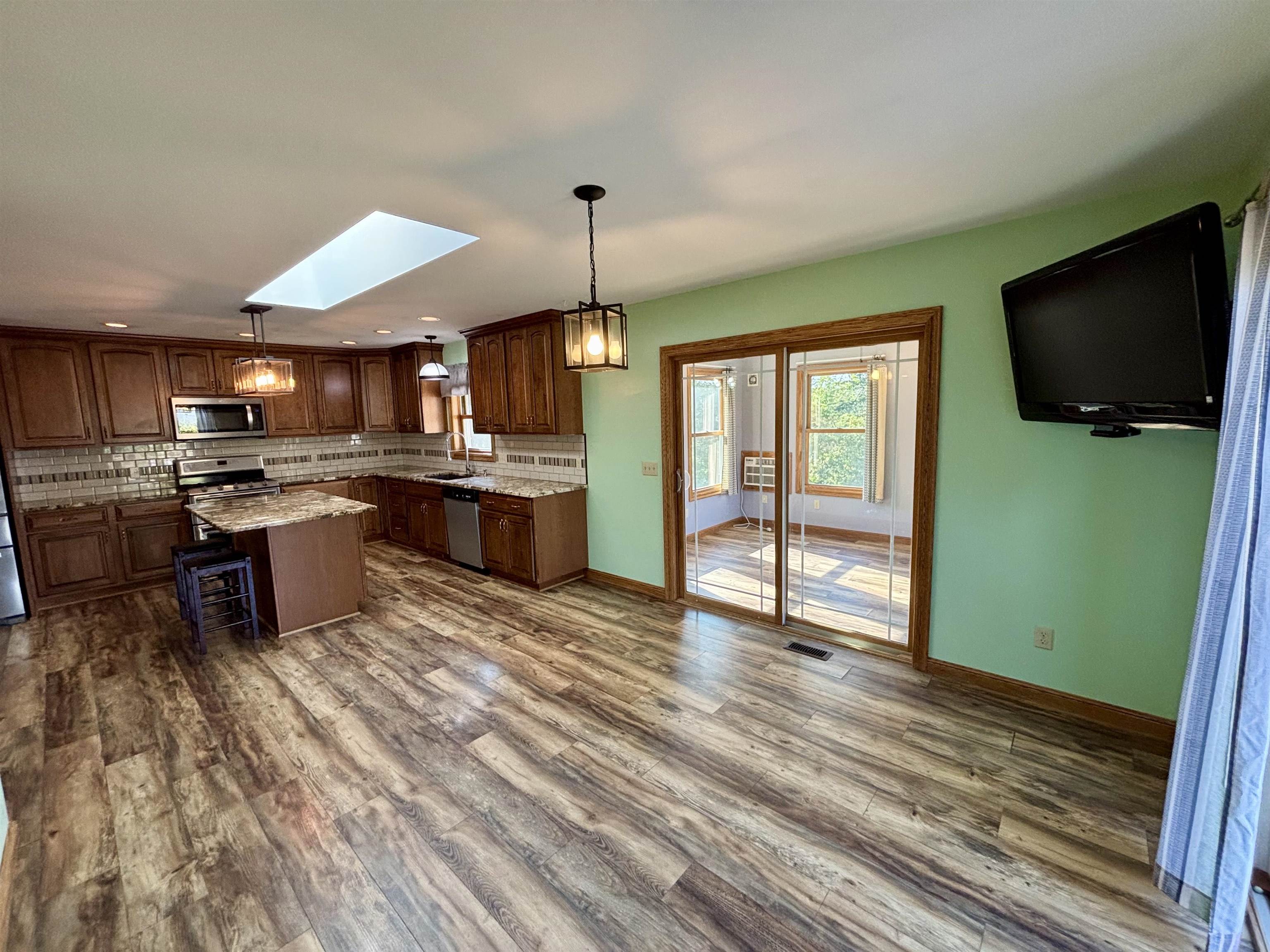3310 South Apple River Road Elizabeth, IL 61028 - Photo 16 of 39 a kitchen with stainless steel appliances granite countertop a stove top oven a sink dishwasher a dining table and chairs with wooden floor