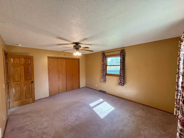 an empty room with windows and ceiling fan
