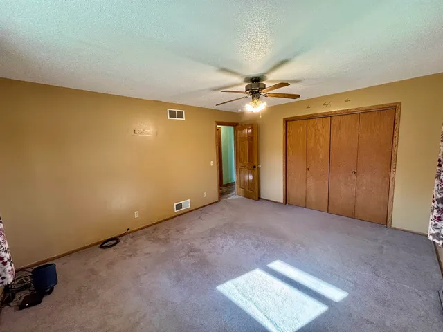 an empty room with a ceiling fan and closet area