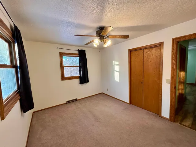 an empty room with windows and fan