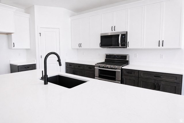 1004 West Paramount Cove South, Unit 315 Ogden, UT 84405 - Photo 13 of 42 Spacious kitchen featuring a large island with an undermount sink and matte black faucet, two-tone cabinetry, stainless steel appliances, and extensive counter space