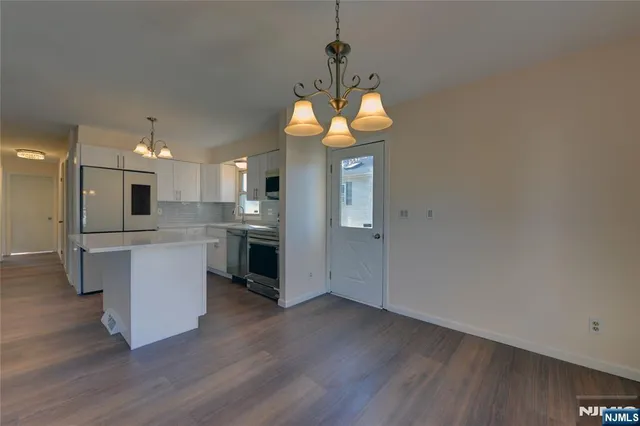 a kitchen with stainless steel appliances granite countertop a refrigerator a sink dishwasher a stove and white cabinets with wooden floor