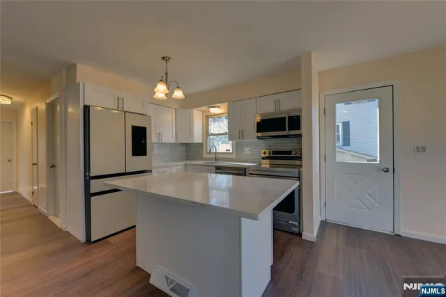a kitchen with kitchen island white cabinets and stainless steel appliances
