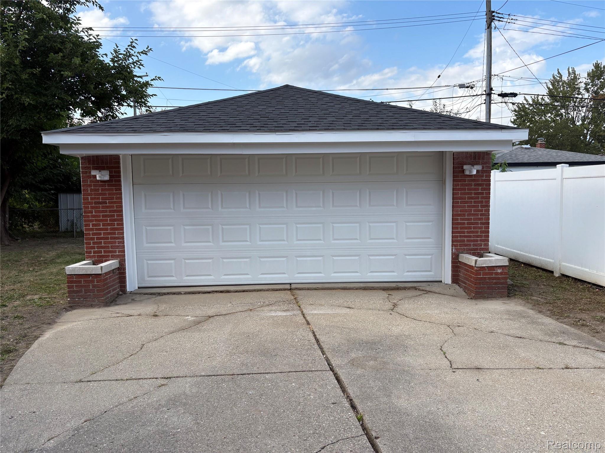18259 Spring Court South Fraser, MI 48026 - Photo 57 of 60 Spacious two-car garage featuring a white paneled overhead door, brick pilasters, and a newly shingled hip roof