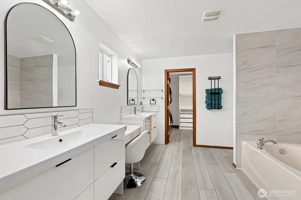 a spacious bathroom with a double vanity sink a mirror a bathtub and shower