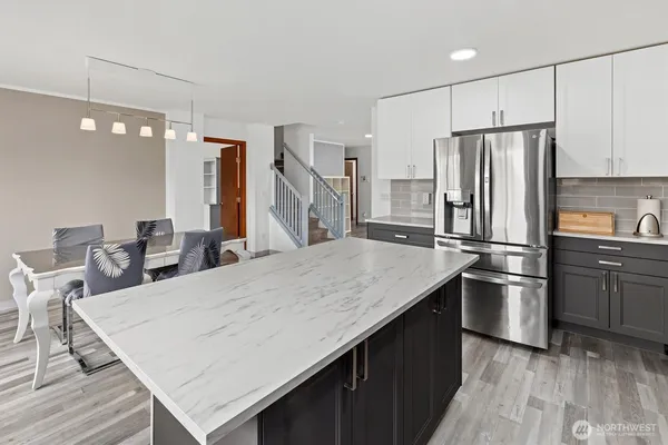 a kitchen with stainless steel appliances a refrigerator a stove a sink dishwasher and white cabinets with wooden floor