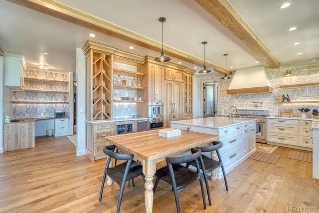 a kitchen with granite countertop a table chairs stainless steel appliances and wooden floor