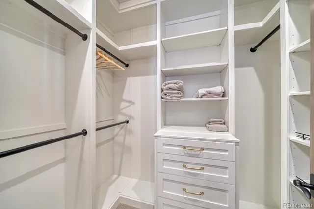 a view of walk in closet with clothes and shoes