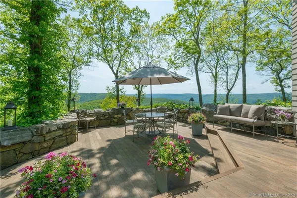 a view of a patio with couches table and chairs potted plants and large tree