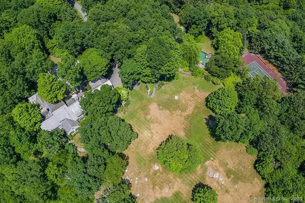 an aerial view of residential house with outdoor space and trees all around