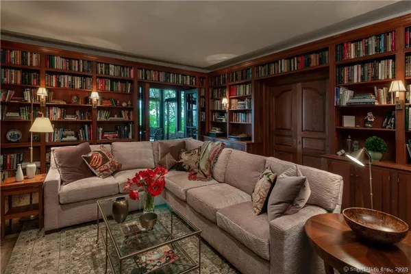 a living room with furniture a bookshelf and a window
