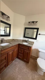 a spacious bathroom with a granite countertop toilet sink and mirror
