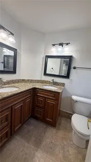 a spacious bathroom with a granite countertop toilet sink and mirror