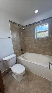 a white toilet sitting next to a bath tub