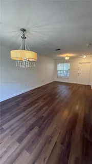 an empty room with wooden floor chandelier fan and windows