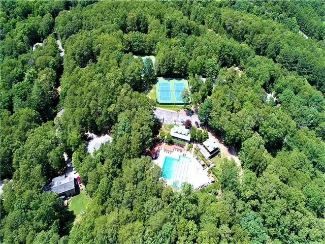 an aerial view of residential house with outdoor space and trees all around