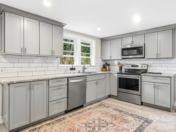 a kitchen with granite countertop a stove a sink and a microwave
