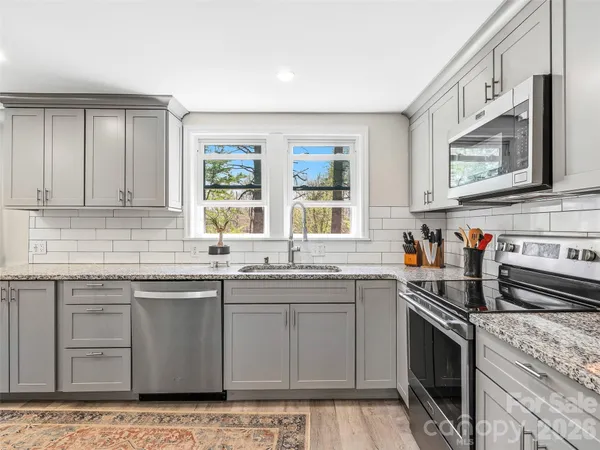 a kitchen with stainless steel appliances granite countertop a sink stove and microwave